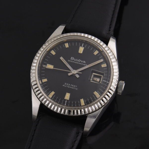 1970s Bulova 36.5mm Oceangrapher stainless steel watch with original 10k gold-fluted bezel, black dial, baton hands, and automatic movement.
