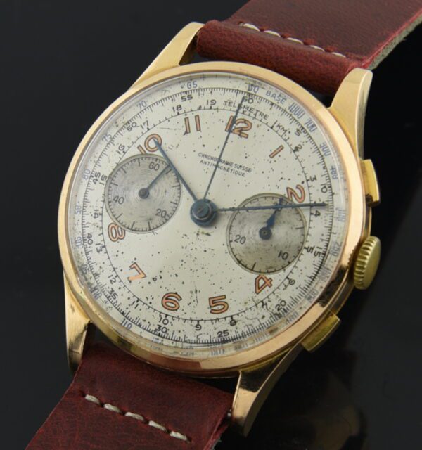 1950s Swiss 37x44.8mm 18k rose gold chronograph watch with evenly aged dial, Arabic numerals, blued steel hands, and brass inner dust cover.