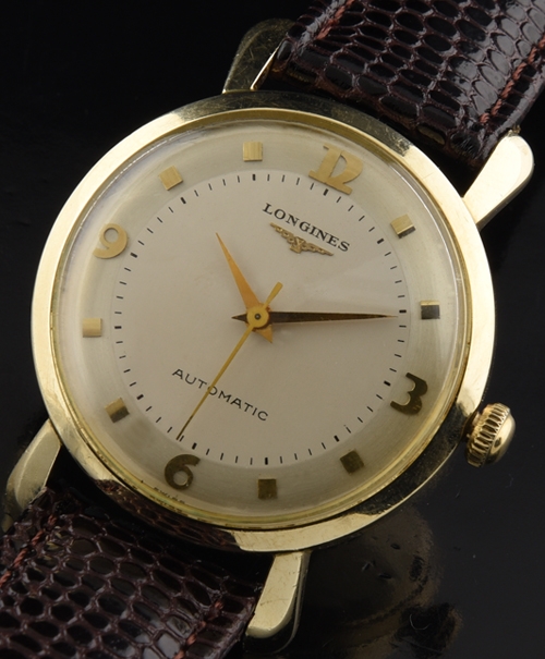 1950s Longines gold-filled watch with original case, extended lugs, dial, Arabic numerals, square markers, and automatic winding movement.