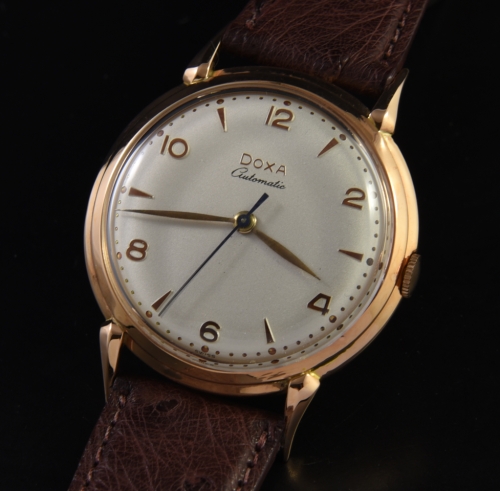 1950s Doxa 14k solid-rose-gold watch with original dial, raised markers, hands, horned/extended lugs, stepped bezel, and automatic movement.
