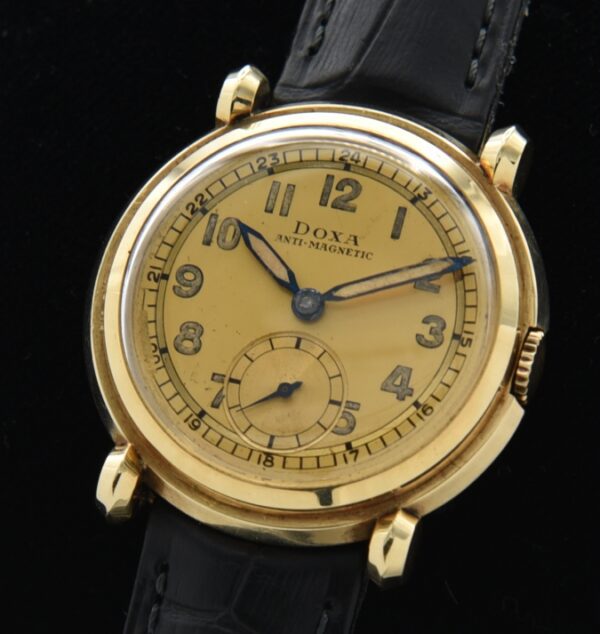 1930s Doxa 14k solid-gold watch with original stepped bezel, circular fixed lugs, dial, 24-hour track, and cleaned manual winding movement.