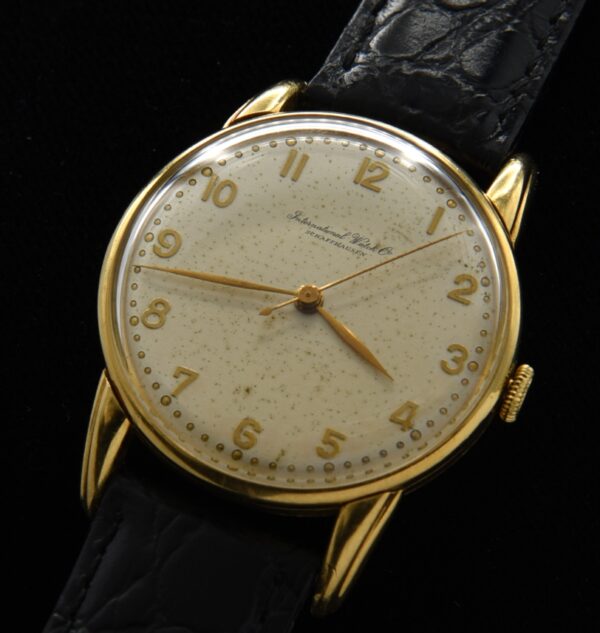 1950s IWC solid 18k yellow gold watch with original elongated lugs, dial, raised Arabic numerals, and manual winding caliber 89 movement.
