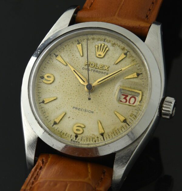 1957 Rolex 34mm Oysterdate stainless steel watch with original dial, gold-toned Arabic markers, Dauphine hands, and manual winding movement.