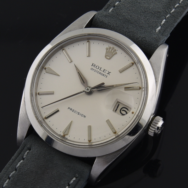 1962 Rolex 34mm Oysterdate stainless steel watch with original Dauphine hands, arrow markers, white dial, case, and manual winding movement.