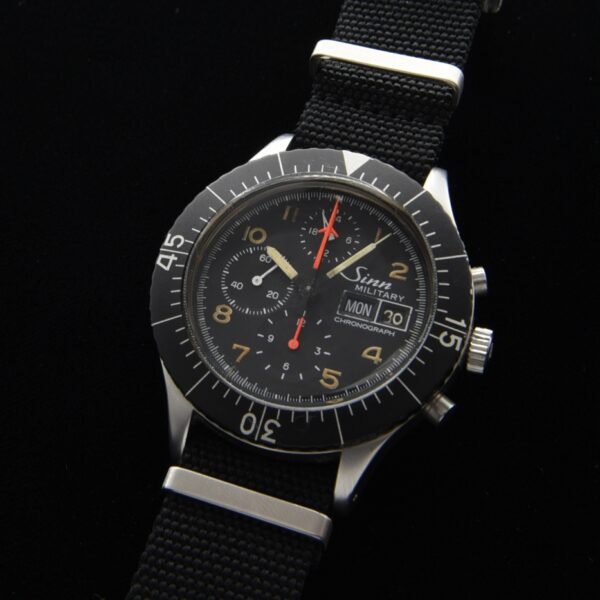 Circa 1985 Sinn 156B chronograph military watch with orange hands, wide-turning bezel, winding crown, and Lemania 5100 automatic movement.