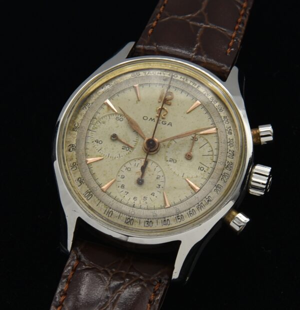 1951 Omega stainless steel chronograph watch with original dial, tachymeter scale, golden arrow markers, and famous caliber 321 movement.