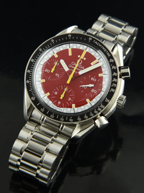 1995 Omega Speedmaster Michael Schumacher edition 40mm stainless steel watch with original box, papers, red dial, and caliber 1143 movement.