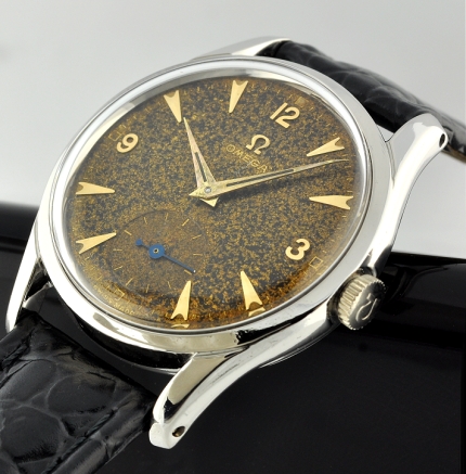 1951 Omega stainless steel watch with original suntanned dial, winding crown, gold-toned markers, Dauphine hands, and caliber 266 movement.