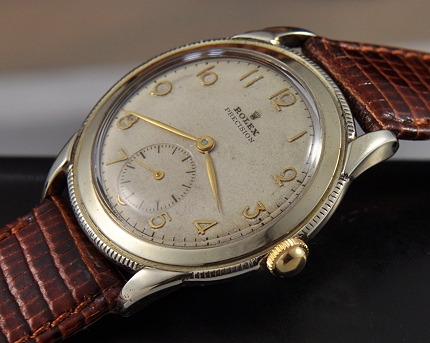 1947 Rolex Precision gold-plated watch with original case, reeded edge, generic winding crown, Arabic numerals, and manual winding movement.